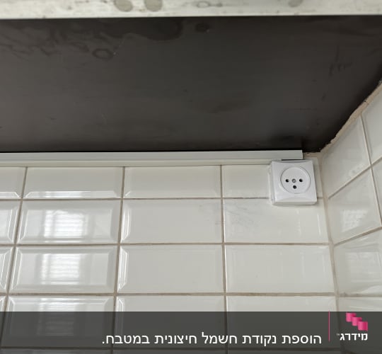 שקע חשמל מותקן על קיר אריחים לבנים